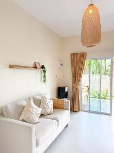 een woonkamer met een witte bank en een raam bij The Palm Villa in Ban Ai Dao