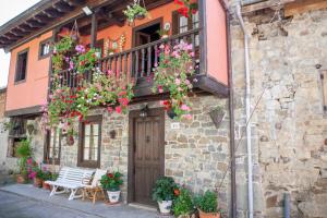ein Gebäude mit Blumen und einem Balkon mit einer Bank in der Unterkunft Casa Rural La Aldea in Pola de Laviana