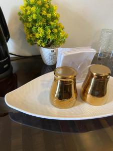 a white plate with two gold jars on a table at Shukra Homestay Hampi,kaddirampura in New Hampi