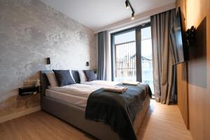 ein Schlafzimmer mit einem Bett und einem großen Fenster in der Unterkunft Laguna Beskidów Resort - Apartamenty Royal in Zarzecze