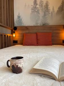a book and a cup of coffee on a bed at Evergreen Lux in Kopaonik +41 photos