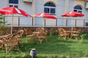 a group of tables and chairs with red umbrellas at فندق جاردينيا بلازا- gardinia plaza in Kafr ‘Işām