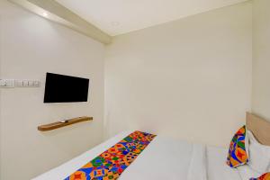 a bedroom with a bed and a tv on the wall at FabHotel Silver Cloud in Warangal +21 photos