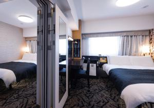 a hotel room with three beds and a window at APA Hotel Morioka Ekimae in Morioka