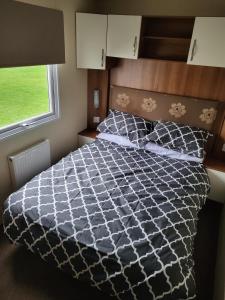 a bedroom with a black and white bed with a window at Caravan by the Sea 640 in Kinmel Bay