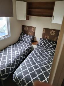 a bedroom with two beds and a window at Caravan by the Sea 640 in Kinmel Bay +12 photos