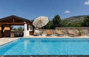 a swimming pool with a umbrella and chairs and a table at Holiday home Lisnjak by Villas Guide in Trbounje
