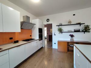 cocina con armarios blancos y suelo de madera en Comfort on the Mountain Side by Holiday World, en Piovene Rocchette