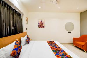 ハイデラバードにあるFabHotel Casa Grandのベッドとオレンジ色の椅子のある寝室