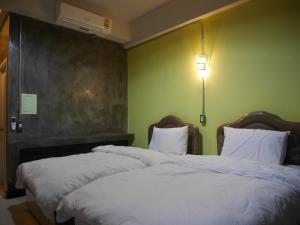 two beds in a room with green walls at Green Garden Place in Udon Thani