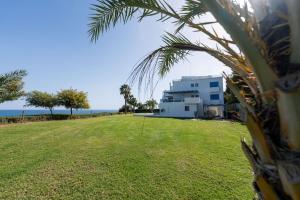 a house on the beach with a palm tree at Beachfront Mediterranean Escape 3bd Sea View Apartment in Pendakomo