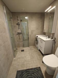 a bathroom with a shower and a toilet and a washing machine at Nice and cloce to the airport 75m2 app in Vantaa