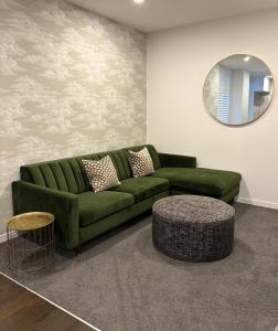 a green couch in a living room with a mirror at Central & Chic in the Capital in Wellington