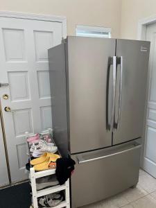 a stainless steel refrigerator in a kitchen next to a door at Modern bedroom in Vancouver West in Vancouver
