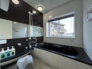 ein Badezimmer mit schwarzem Waschbecken und Fenster in der Unterkunft 南欧風のゴージャスなオーシャンビラ オーシャンビュー 1棟貸切 バーベキュー 長期滞在 ファミーユ伊豆高原 in Ito + 20 Fotos