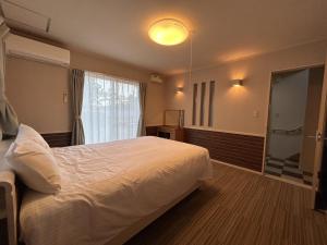 ein Schlafzimmer mit einem weißen Bett und einem Fenster in der Unterkunft 南欧風のゴージャスなオーシャンビラ オーシャンビュー 1棟貸切 バーベキュー 長期滞在 ファミーユ伊豆高原 in Ito