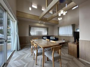 ein Esszimmer mit Tisch und Stühlen und einer Couch in der Unterkunft 南欧風のゴージャスなオーシャンビラ オーシャンビュー 1棟貸切 バーベキュー 長期滞在 ファミーユ伊豆高原 in Ito