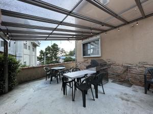 eine Terrasse mit Tischen, Stühlen und einem Grill in der Unterkunft 南欧風のゴージャスなオーシャンビラ オーシャンビュー 1棟貸切 バーベキュー 長期滞在 ファミーユ伊豆高原 in Ito