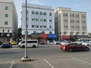 una strada cittadina con auto parcheggiate davanti agli edifici di Muscat Women's Hostel a Mascate