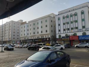 un'auto parcheggiata in un parcheggio di fronte agli edifici di Muscat Women's Hostel a Mascate