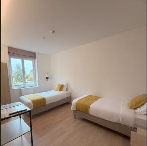 a room with two beds and a table and a window at Maison Des Augustines in Saint-Amand-les-Eaux
