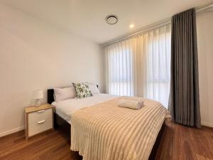ein Schlafzimmer mit einem Bett mit gestreifter Decke und einem Fenster in der Unterkunft Blue Haven Retreat - Marsden Park Townhouse in Marsden Park