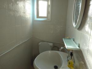 a bathroom with a toilet and a sink and a window at tagermess 1 in Midoun