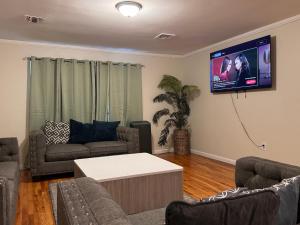 ein Wohnzimmer mit einer Couch und einem Fernseher an der Wand in der Unterkunft Urban haven 3 Kings bedroom near EWRNYC DTW in Newark