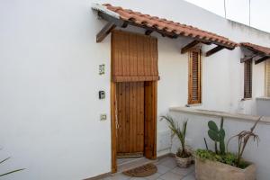 una casa bianca con una porta in legno e alcune piante di Adriatic Suite - Casa vacanze nel Salento a SantʼAndrea