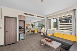 a living room with a yellow couch and a kitchen at Novotel Dubai World Trade Centre in Dubai +98 photos