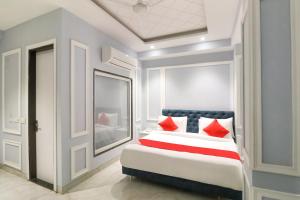 a bedroom with a king sized bed with red pillows at Hotel O Lax in New Delhi