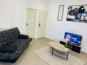 a living room with a couch and a table at Cosy T2 CLIM FIBRE Centre ville RDC in Marmande +7 photos