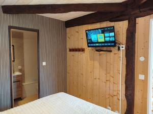 a bedroom with a tv on a wooden wall at Gite de la chapelle in Nogaro