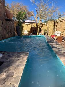 a swimming pool with blue water in a backyard at Hostal Katarpe in San Pedro de Atacama