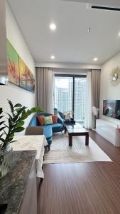 a living room with a blue couch and a table at Masteri Pearl Apartment - Luxury view in Ocean Park 1 in Gia Lâm Pho