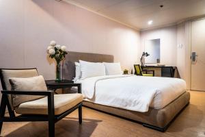a bedroom with a bed and a chair and a vase of flowers at Green Sun Hotel in Manila