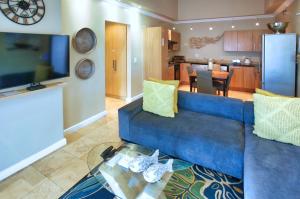 a living room with a blue couch and a kitchen at Ellefsen Golf Suite 108, Langebaan, 4-sleeper in Langebaan