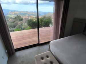 ein Schlafzimmer mit großem Fenster mit Blick auf eine Holzterrasse in der Unterkunft Chambre entre mer et montagne in Barbaggio