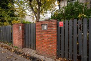 a fence with a brick wall and a gate with a window at Łódź Urban Serenity Studio #11 by BookingHost in Łódź
