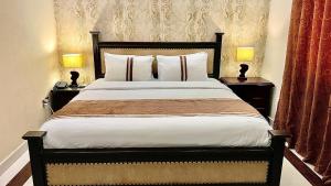 a bedroom with a large bed with two lamps on tables at Royal Inn Hotel in Karachi