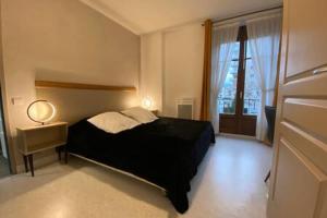 L'Ecrin de Verdure du Centre Ville في إيكس لي بان: غرفة نوم بسرير اسود ونافذة
