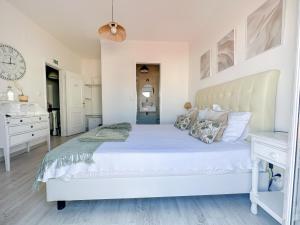 a white bedroom with a large bed and a desk at Casa da Alagoinha by Umbral in Vila Nova de Milfontes
