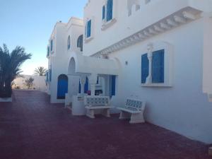 a white building with two benches in front of it at taguermess 2 in Midoun
