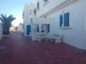 a white building with benches on the side of it at taguermess 2 in Midoun +1 photo