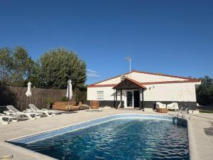 a swimming pool with chairs and a house at Las Colinas in Illana