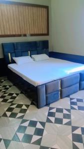 a blue bed in a room with a checkered floor at Anha Farmstay in Mādho Tānda