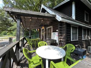 a deck with green chairs and a table and a grill at 松川湖の目の前に佇む貸切ログハウス ファミーユ松川湖 in Ito