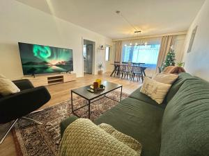 a living room with a green couch and a flat screen tv at Aurora City View Suite in Rovaniemi