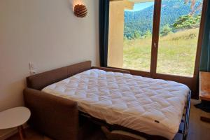 una cama en una habitación con una ventana grande en Les Cimes - La Canopée, en La Ville