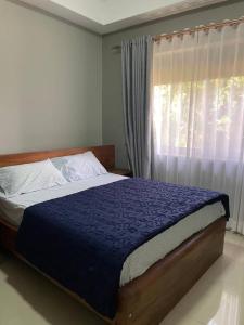 a bedroom with a bed with a blue comforter and a window at Kata furnished accomodation 